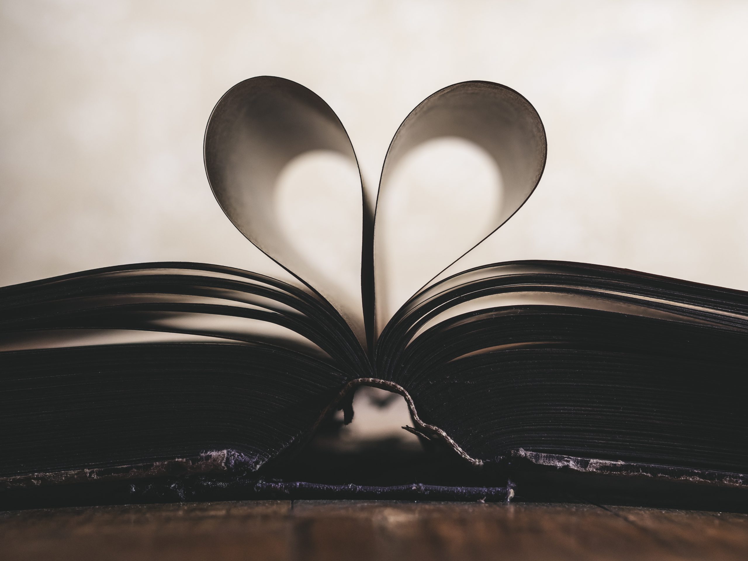Ein Buch liegt offen auf einem Tisch, man sieht es im Profil. Zwei Seiten bliden ein Herz.